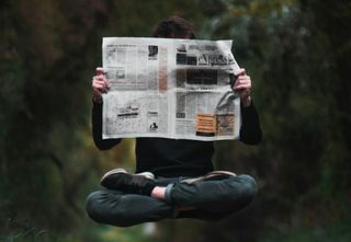 A person levitating and reading a newspaper.